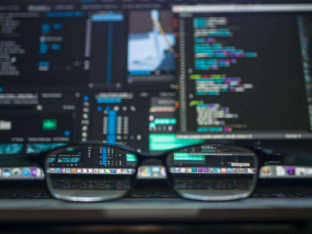 Glasses on top of a table focused on a computer screen, representing the Singapore Tech.Pass visa for talented IT-specialists