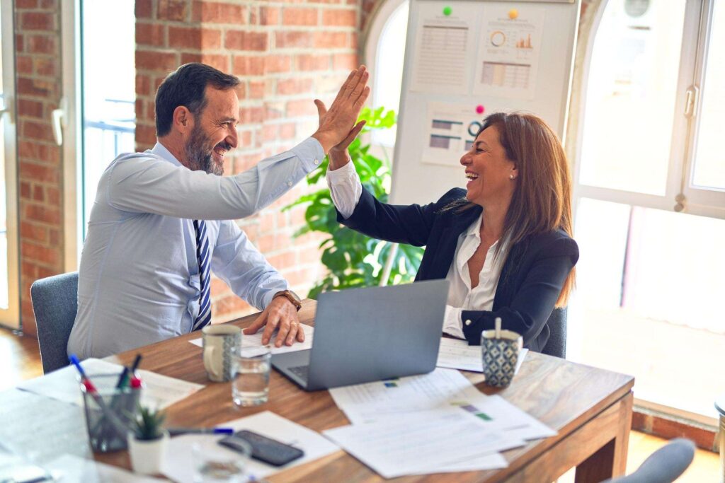 Two business owners giving each other a high five after choosing the right type of business and legal structure