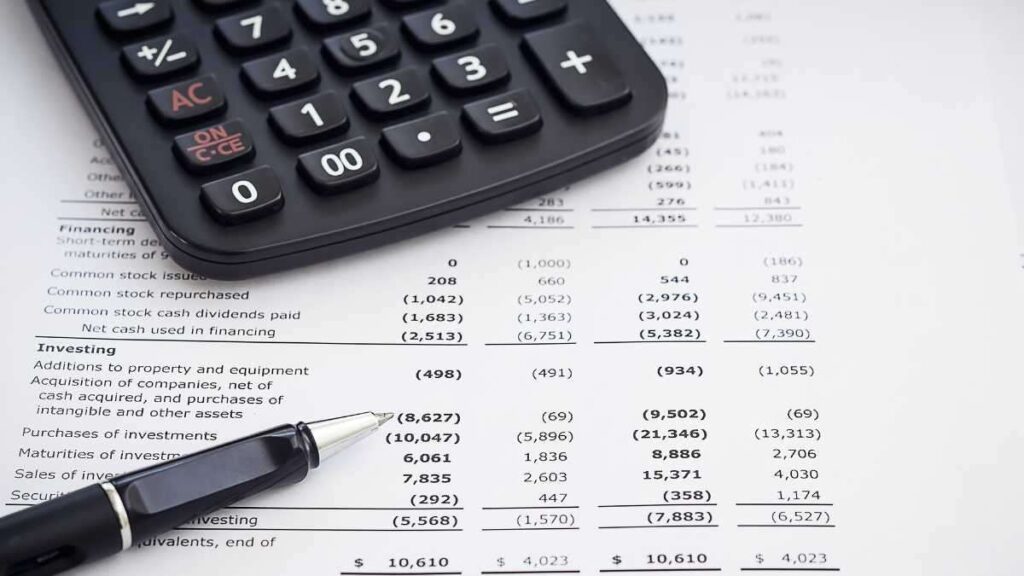 Financial statements with pen and calculator on top representing accurate accounting in Singapore.