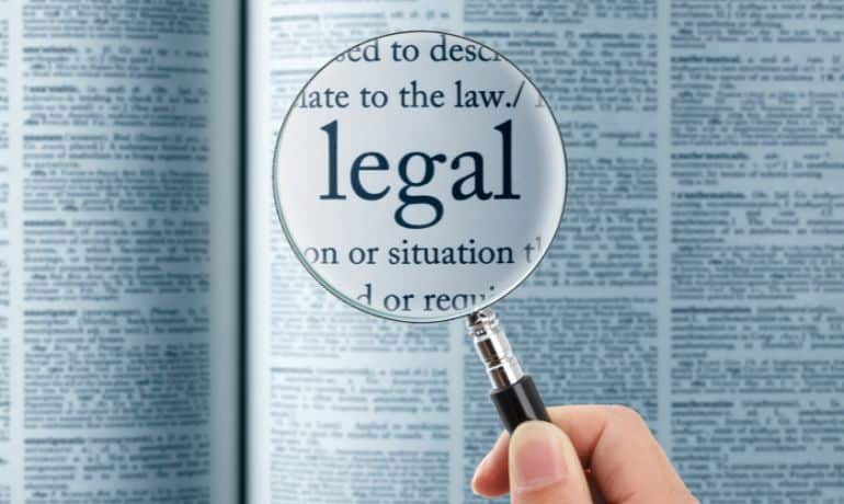 Magnifying glass focusing on the word "legal" of a book to represent apostille and legalization