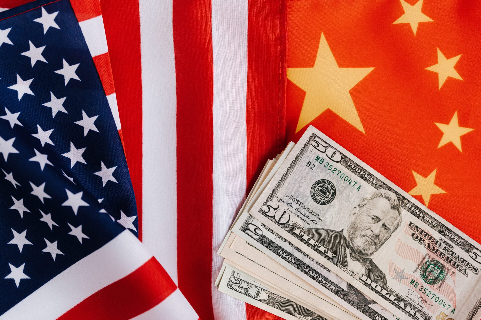 United States and China flags with cash money on top, representing USA's plan to end dependence on China for Rare Earths