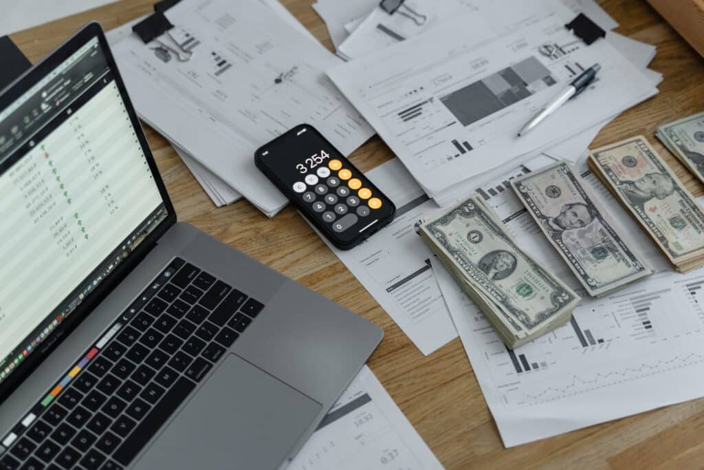 Desk with a computer, cash, calculator, and financial documents explaining the different accounting standards in Singapore: International Financial Reporting Standards (IFRS), Singapore Financial Reporting Standards (SFRS), and Singapore Financial Reporting Standards for Small Entities (SFRS for SE)